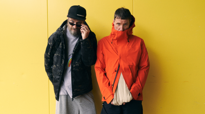 Artist Sleaford Mods standing in front of a yellow wall